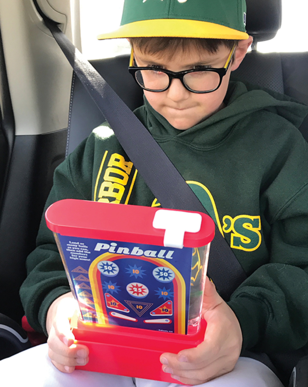Boy in car seat playing classic handheld game Original Waterfuls with pinball design and water-based play.