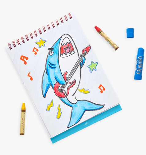 Awesome Doodles Sketchbook showing a colorful shark playing guitar doodle with crayons nearby on white background.