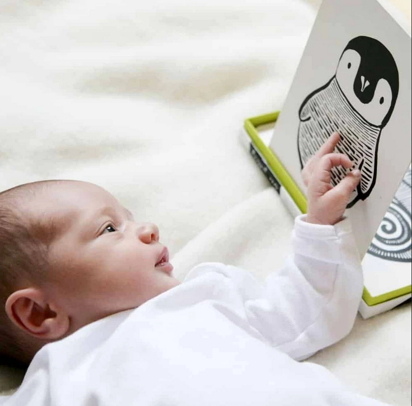 Baby lying down reaching towards a Penguin card from the Black & White Art Cards set promoting visual development.