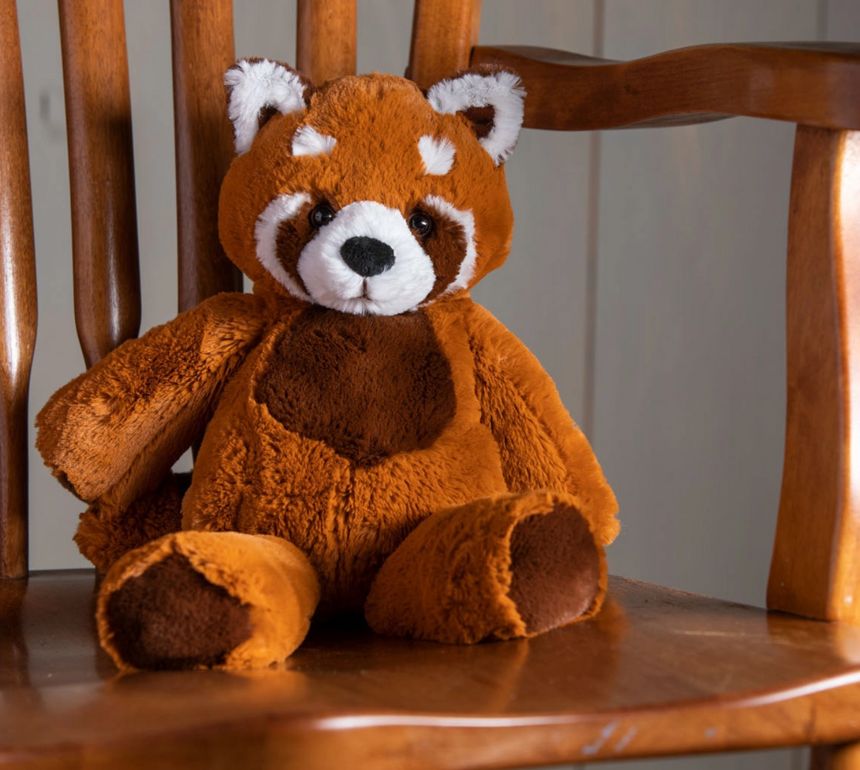 Marshmallow Red Panda plush toy sitting on wooden chair with soft, floppy fabric and embroidered details.