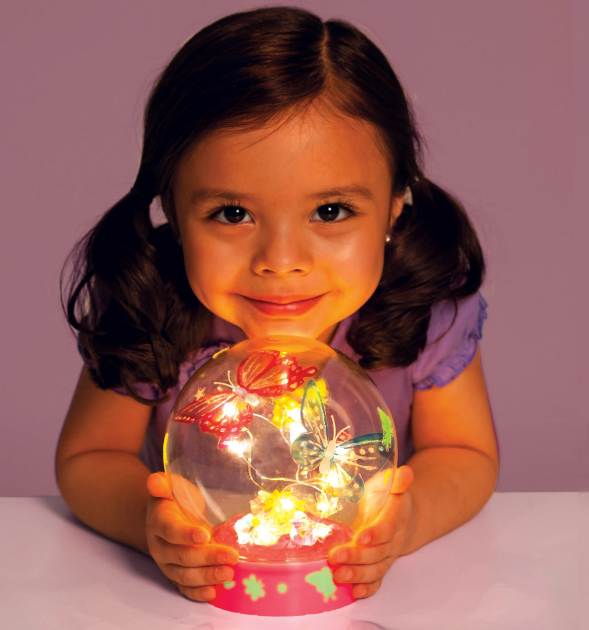 Young girl holding illuminated Butterfly Fairy Lights globe with colorful butterflies and LED lights inside.