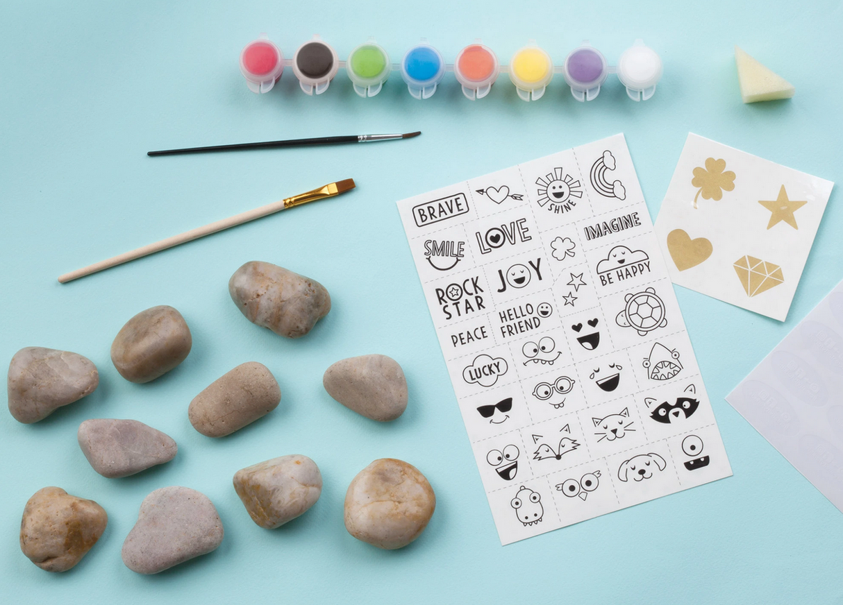 Hide & Seek Rock Painting Kit with natural river rocks, water-resistant paints, brushes, and waterproof transfer designs on blue background.