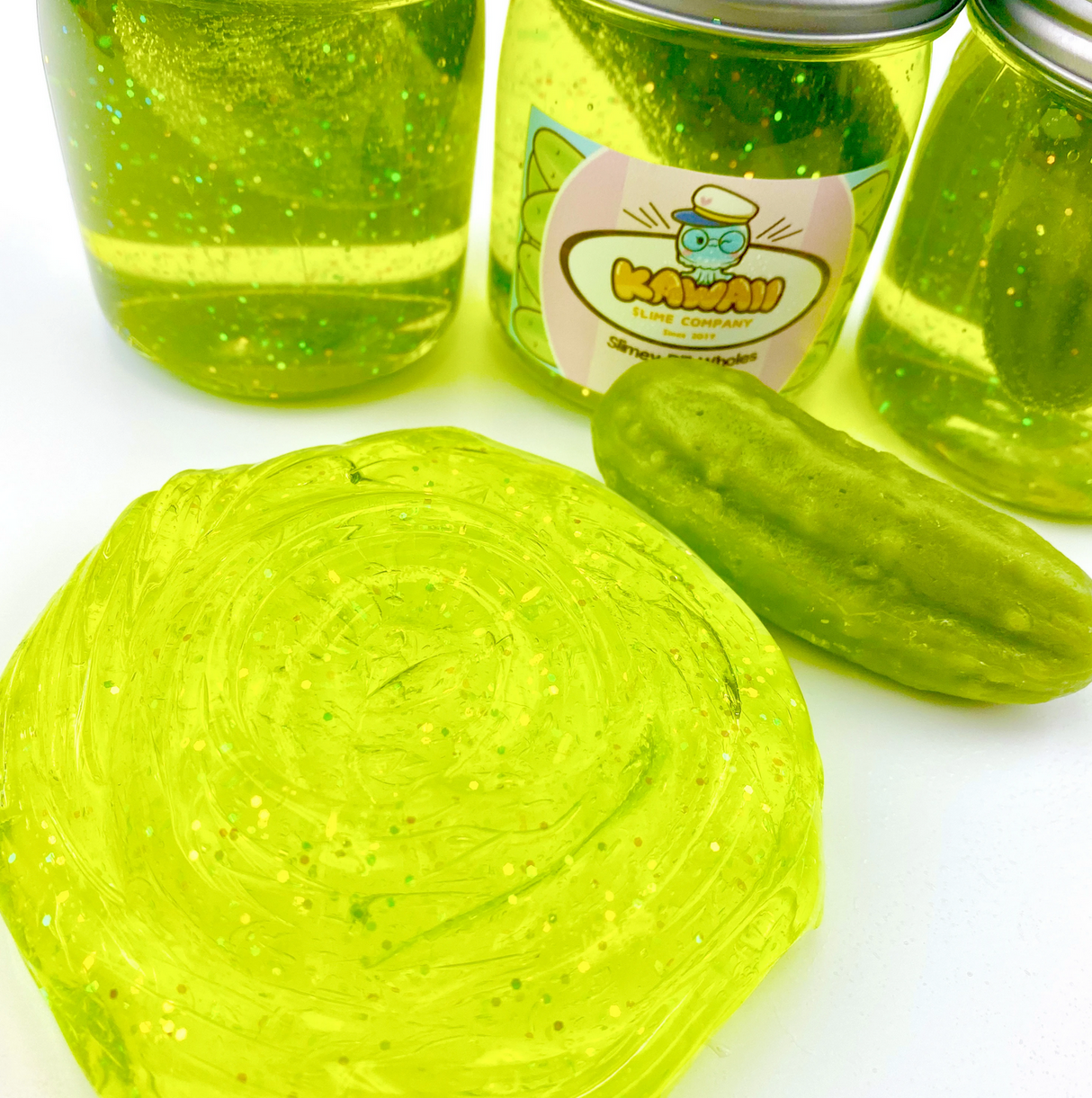 Shimmery Pickle Clear Slime with glitter and pickle scent, displayed with jars and a miniature pickle eraser.