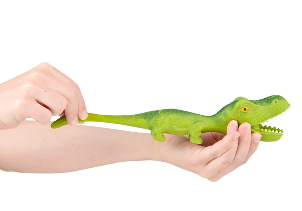 Hand stretching a green squeezy toy alligator showing its stretchy tail, called Stretchy Sand Dino.