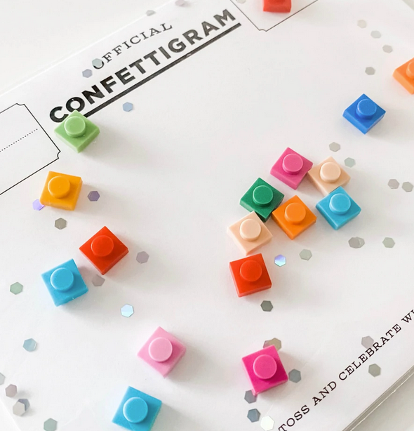 Bricks Confettigram Card with colorful brick-shaped confetti floating over a white message card in a clear envelope.
