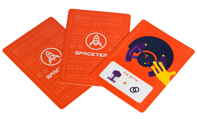 Spaceteam card game showing bright red cards with spaceship repair instructions and team branding.
