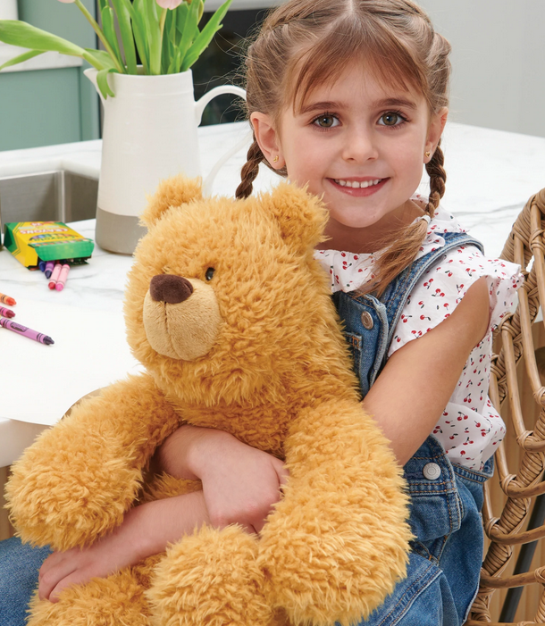 Young girl smiling and hugging a 15” classic brown Teddy Bear Growler plush with soft fur and round paws