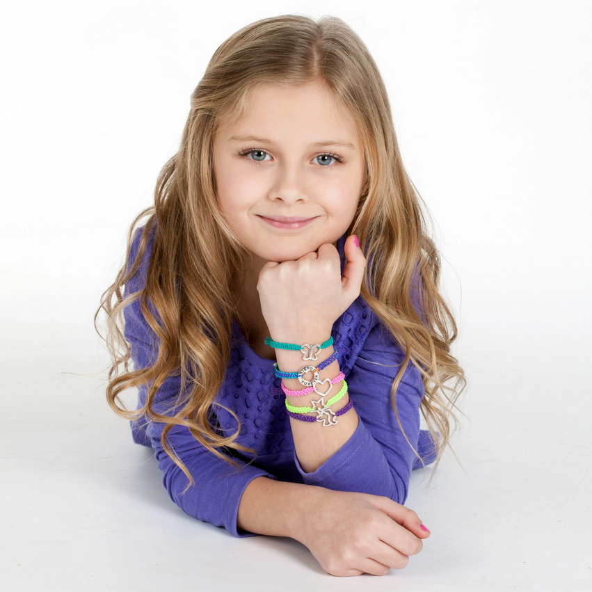 Girl smiling and wearing colorful Friends Forever Bracelets with silver charms on her wrist, showcasing DIY jewelry craft.