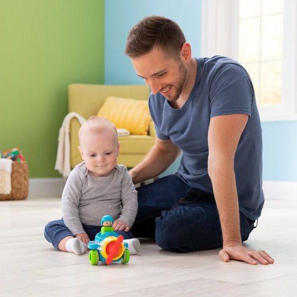 A baby and father playing on the floor with the colorful Press & Go Airplane toy for infants.