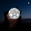 Hand holding glowing Waboba Moon Ball | Moonshine against dark night sky with visible moon in background.