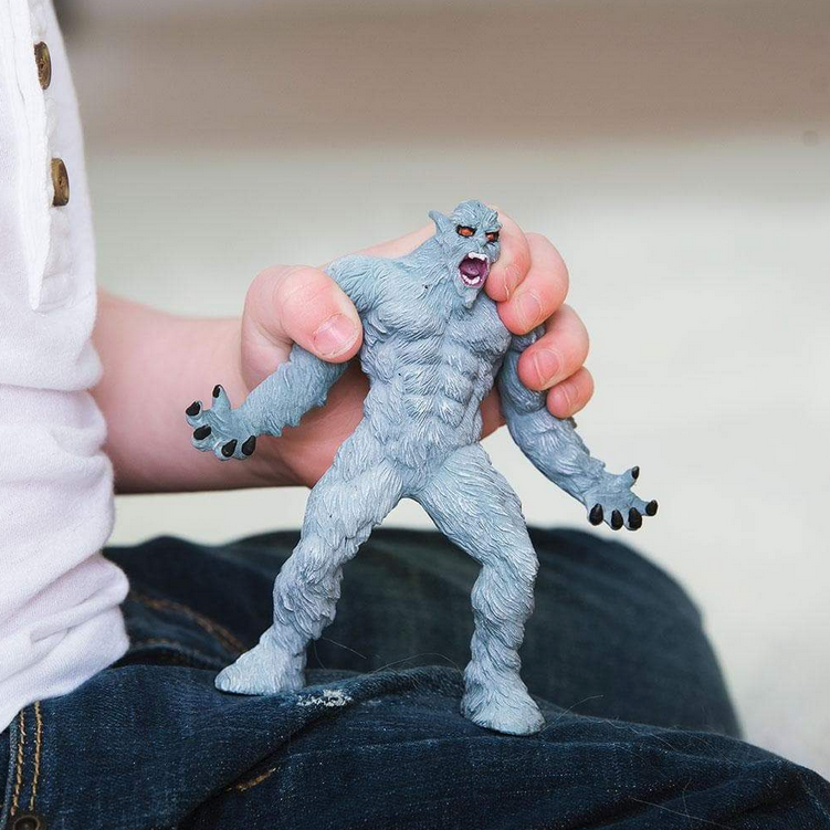 Yeti figure with light blue fur, red eyes, and open mouth held in a child's hand, showing detailed texture.