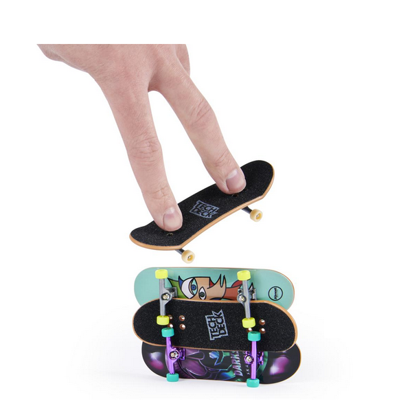 Hand using Tech Deck Sk8shop Bonus Pack fingerboard above two stacked mini skateboards with colorful designs.