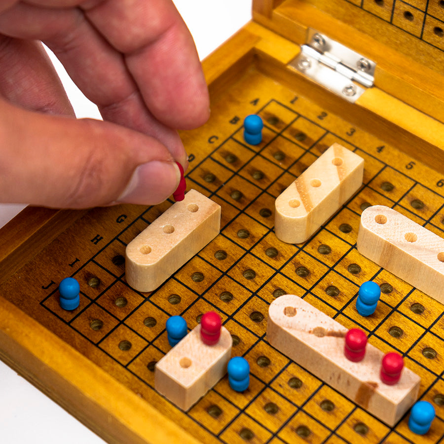 Close-up of wooden game pieces and pins on the Sea Battle board game during gameplay.