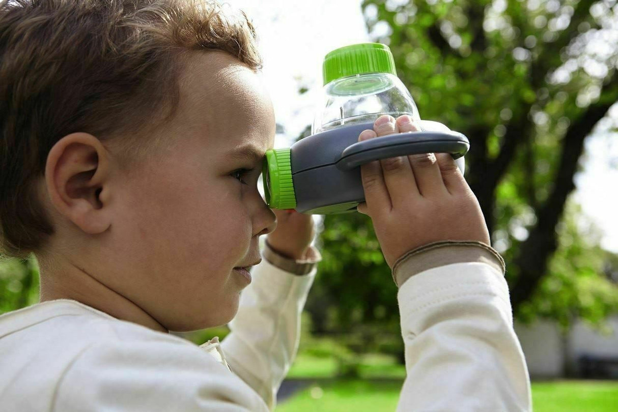 Child examining nature outdoors using Terra Kids Exploration Magnifying Glass with dual handles and magnification features.