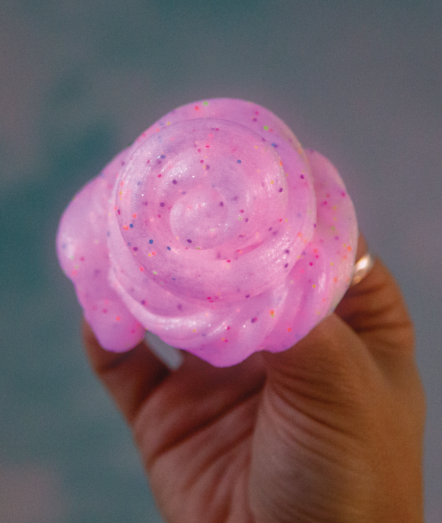 Glowbrights Enchanting Unicorn Thinking Putty glowing pink with rainbow glitter held in hand.
