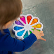 Child playing with colorful Dimpl Digits silicone number-learning toy with tactile bubbles for counting and motor skills.