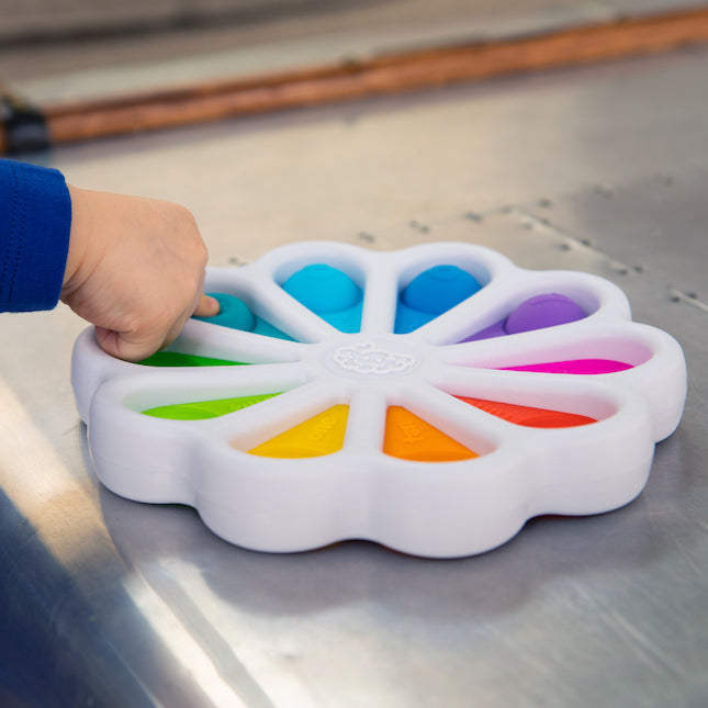 Child pressing colorful silicone bubbles on Dimpl Digits toy for tactile number learning and fine motor skills development.