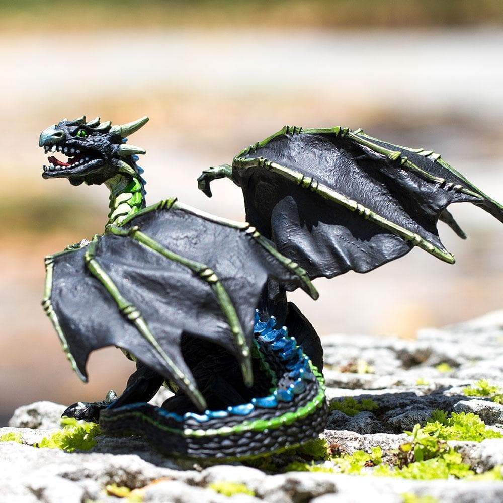 Fog Dragon figure with black bony wings, green and blue accents, posed outdoors on mossy rocks.