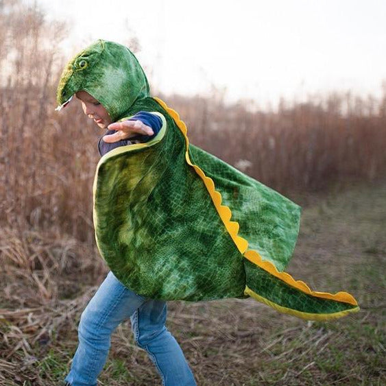 Child wearing a green T-Rex Hooded Dinosaur Cape with tail and textured hood outdoors playing.