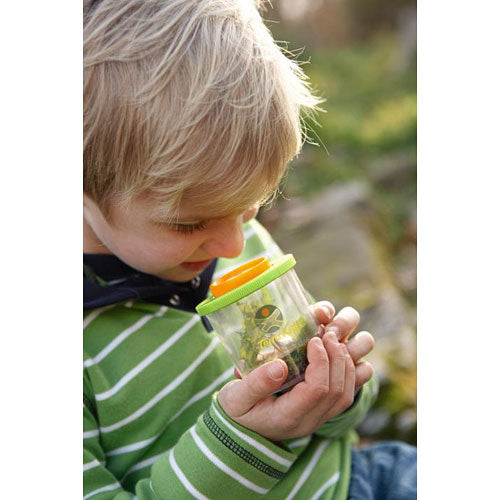 Child exploring outdoors with Terra Kids | Beaker Bug Magnifier observing a plastic spider inside the jar.