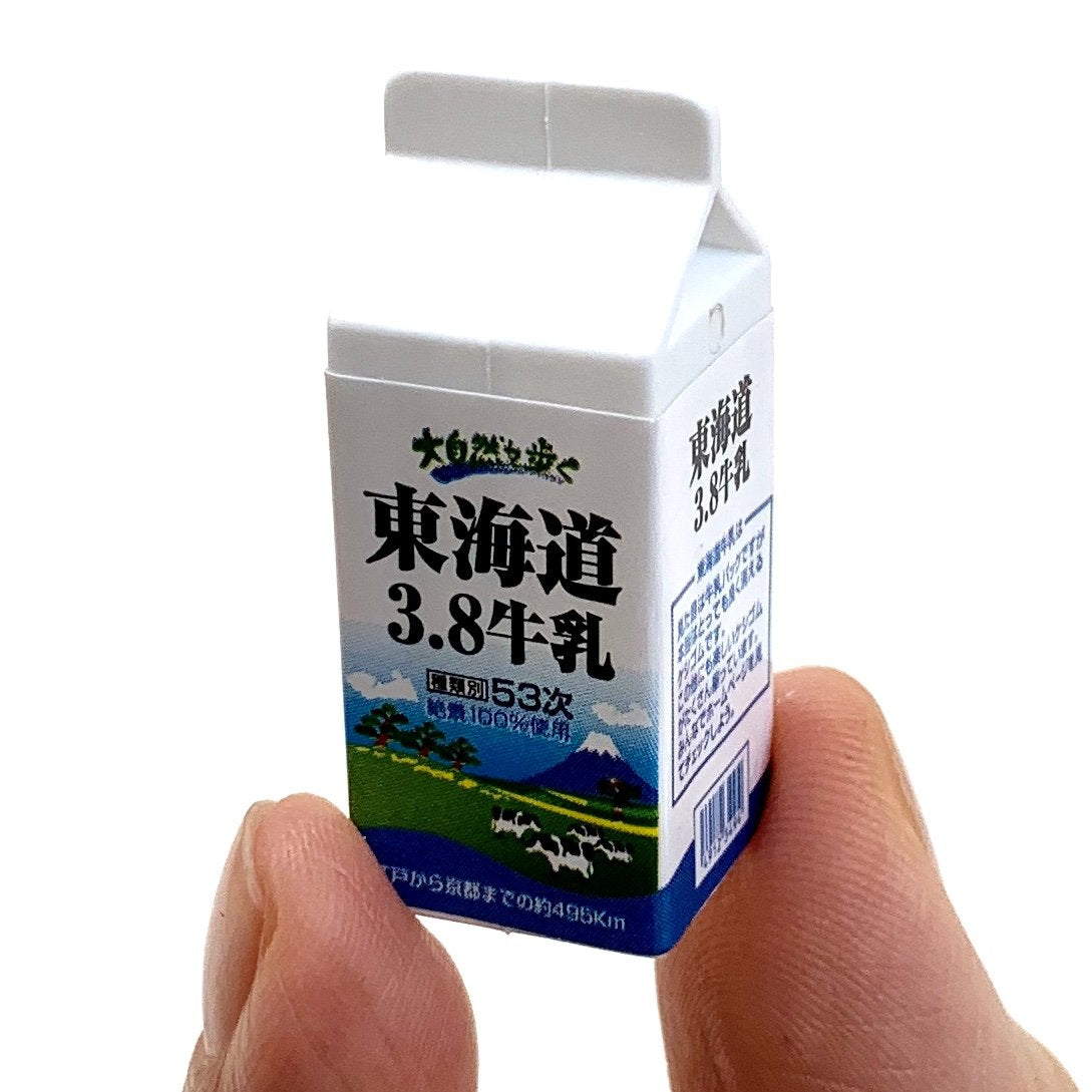 Japanese Eraser Drink showing a miniature milk carton puzzle eraser toy held between fingers, eco-friendly and handmade.