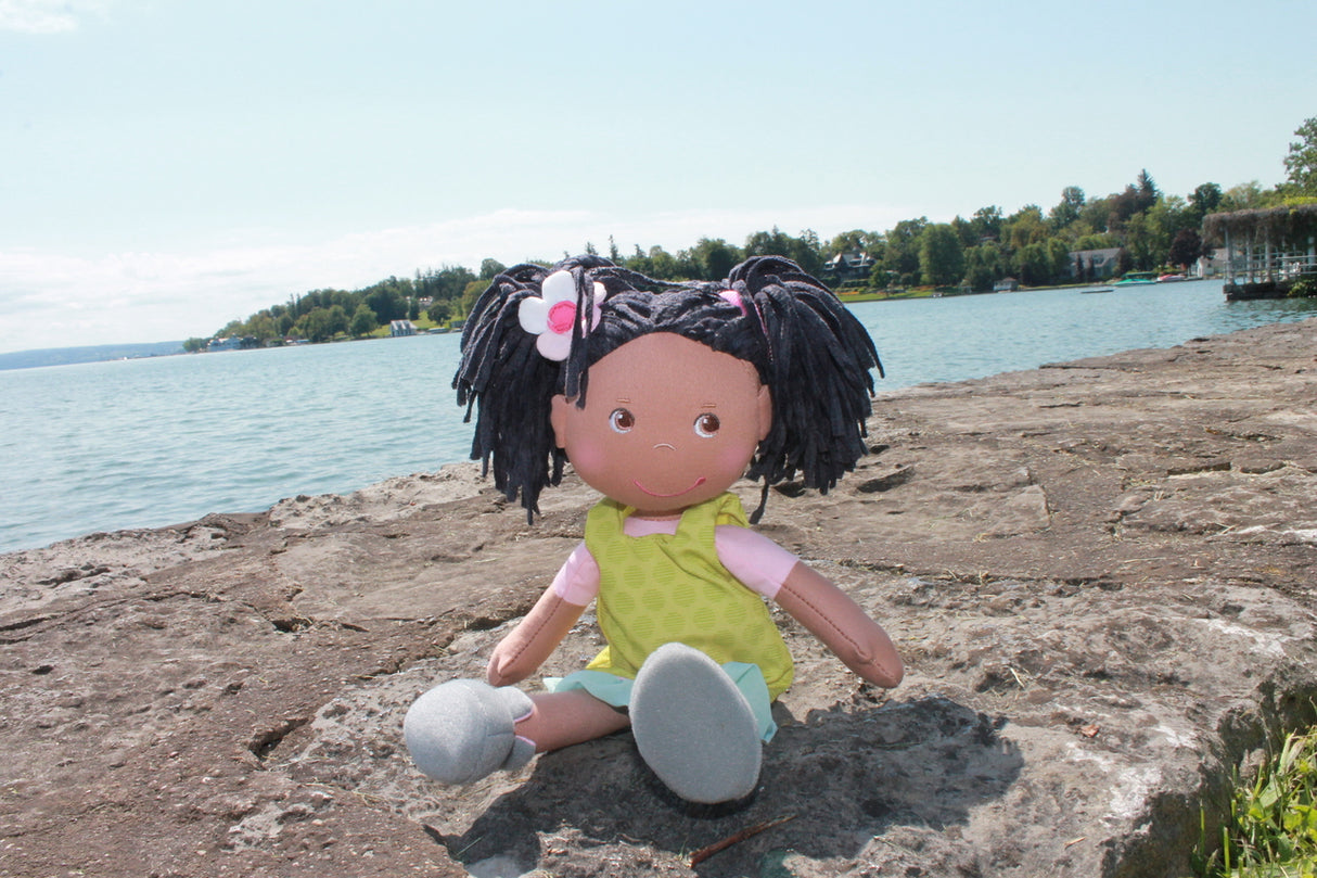 Soft Doll | Cari sitting on a rocky lakeside with chenille hair, green dress, and sewn-on shoes on a sunny day.