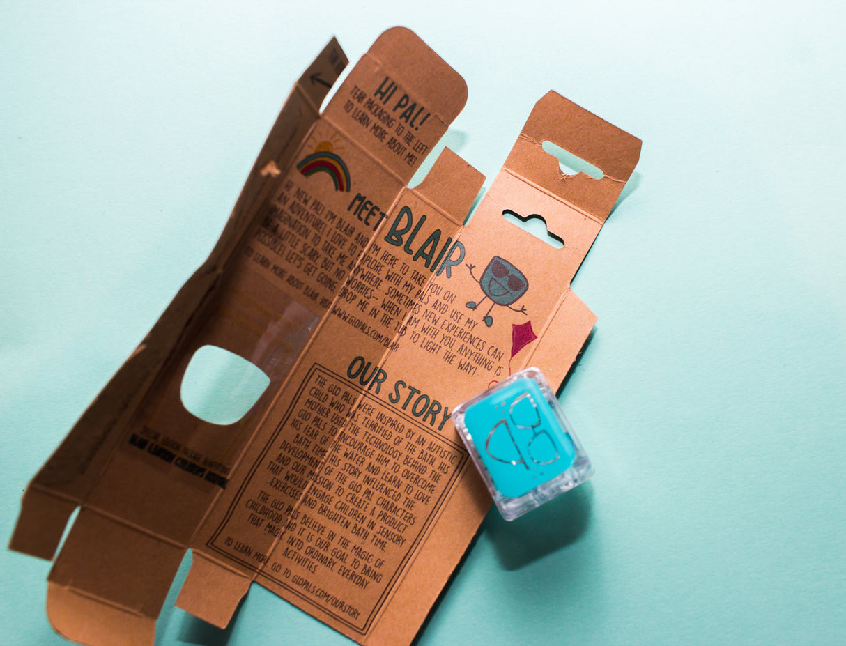 Glo Pals Blue light-up cube with big glasses character and brown product packaging on a blue background.