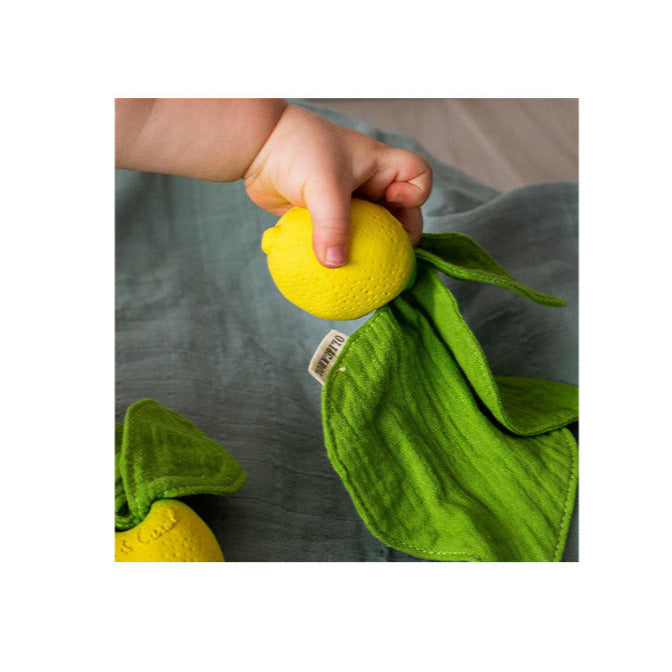 Baby holding Mini DouDou Teether | John Lemon with soft green muslin and natural rubber lemon teether.