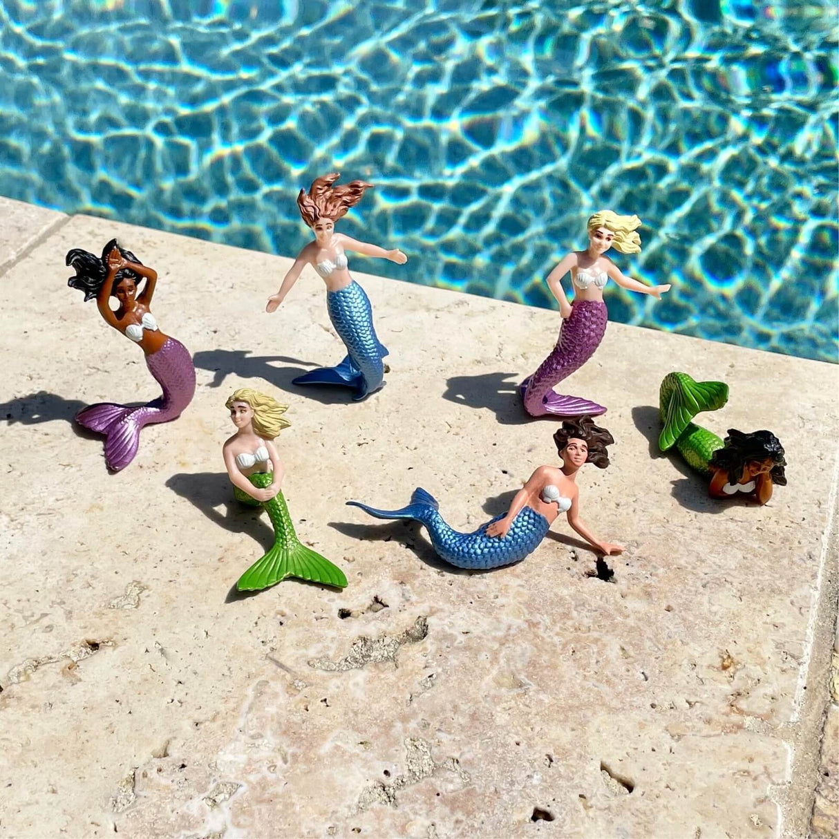 TOOB | Mermaids set with six colorful, detailed mermaid figurines posed by a pool on light stone tiles.