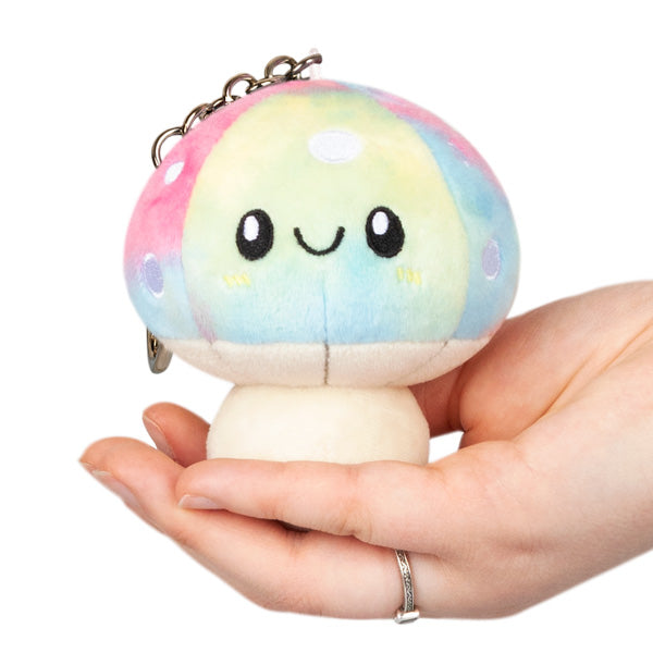 Hand holding a colorful plush Mushroom Micro keychain with a smiling face and metal clip attached.