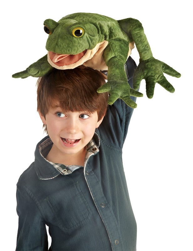 Child playing with a green textured and warty Toad Puppet with animated mouth and forelegs on white background