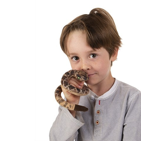 Child playing with a coiled Folkmanis Mini Rattlesnake Finger Puppet featuring printed snakeskin and a rattle.