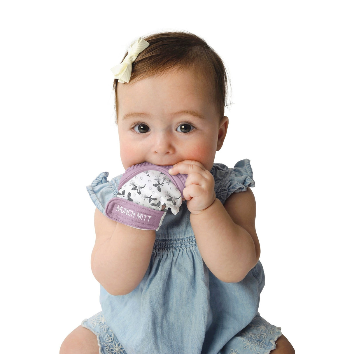Baby wearing Munch Mitt | Lilac Bloom teething mitten, providing safe and soothing relief for infants.