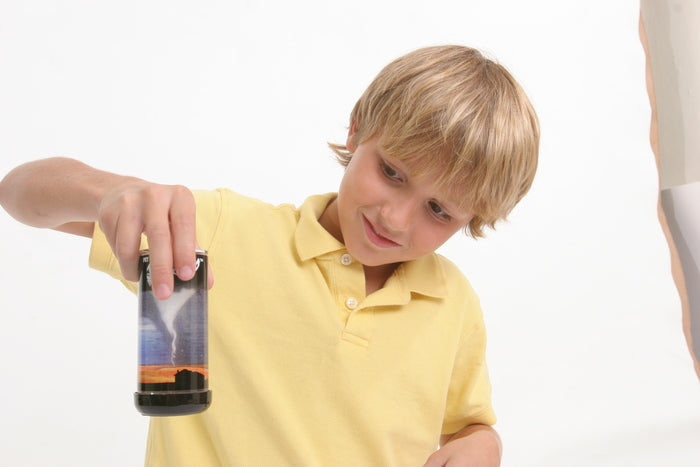 Young boy holding and observing the Pet Tornado Tube demonstrating a swirling funnel tornado effect.