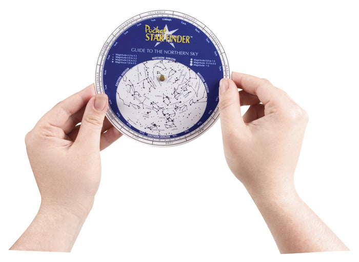 Hands holding the Pocket Star Finder, a compact star chart for locating constellations in the northern sky.