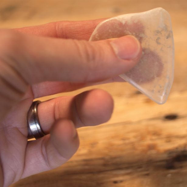 Hand holding TV Rock demonstrating the fiber-optic effect projecting images onto its surface on wood table.