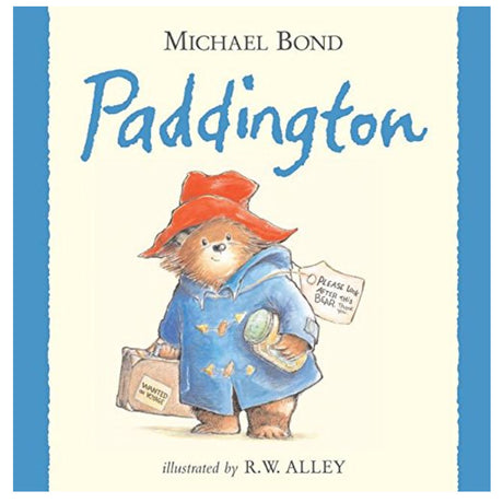 Cover of Paddington featuring the bear in a blue coat and red hat holding a suitcase and marmalade jar.
