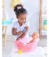 Young girl playing with a pink bathtub and shower set, washing a doll with water from the toy showerhead