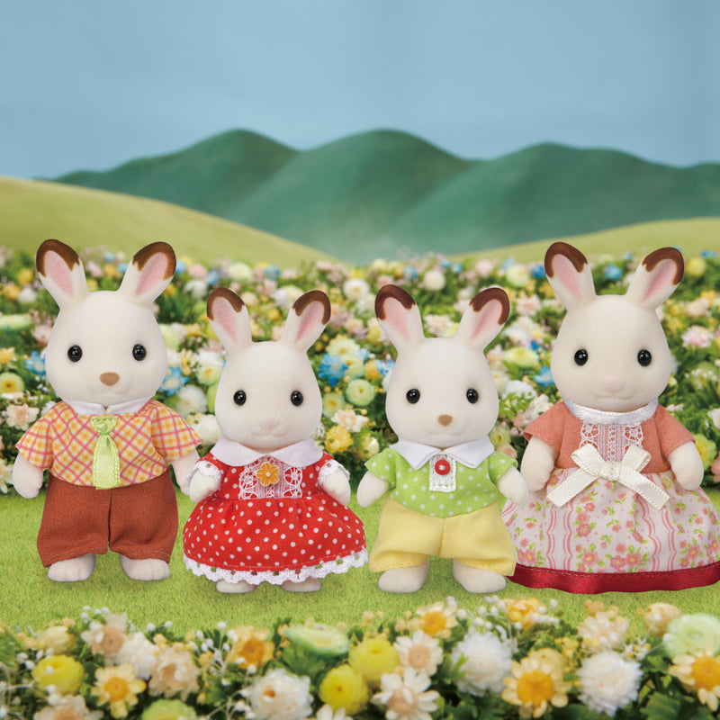 Chocolate Rabbit Family with four white rabbits in detailed clothes standing in a flower field with green hills background