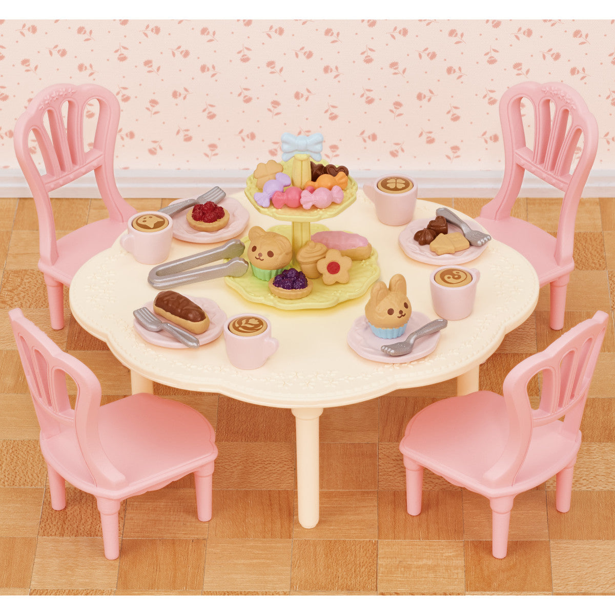 Sweets Party Set with pink chairs tea cups plates and colorful pastries on a table