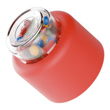 Red rounded device with clear top showing colorful small balls inside for tactile interaction