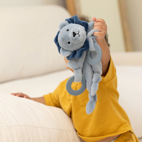 Baby holding a soft plush lion teether buddy with soothing rings and gentle rattle for infants to cuddle and chew