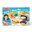 Child playing with a colorful play set that includes fabric pie crust, rolling pin, pie tins, and toy oven accessories