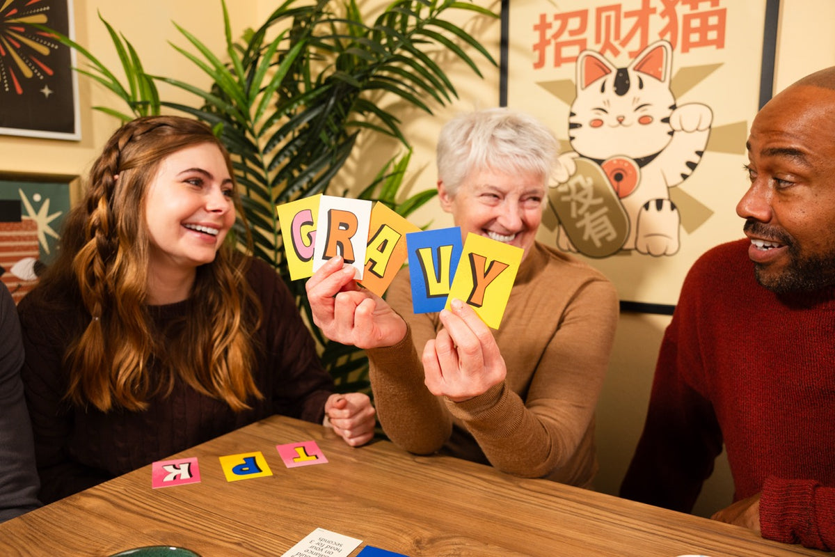 Pounce game with friends holding colorful letter cards during a lively tabletop game