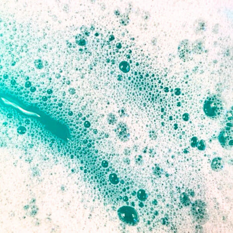 Close-up of foaming aquamarine bubbles created by Little Whale Bath Co Bubble Bath, a moisturizing, plant-based bath powder.