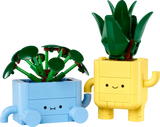 Botanicals Happy Plants building set with baby dracaena in yellow pot and baby pilea in blue pot with smiling faces.