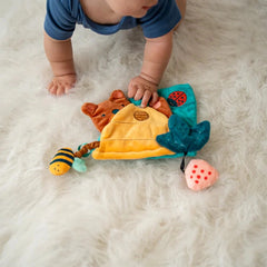 Happy Hive Sensory Book with baby exploring colorful textured fabric pages on a soft white rug