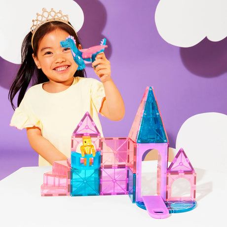 Child playing with colorful Magnatiles Castle building set featuring towers, drawbridge, dragon figure, and royalty figure.
