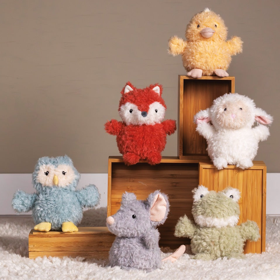 Again Friends Rattle displayed with colorful plush animal toys on wooden boxes