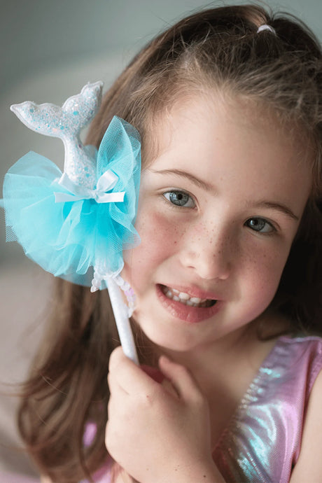 Little girl holding a glittery Mermaid Wand with soft blue tulle fluff and mermaid tail detail.